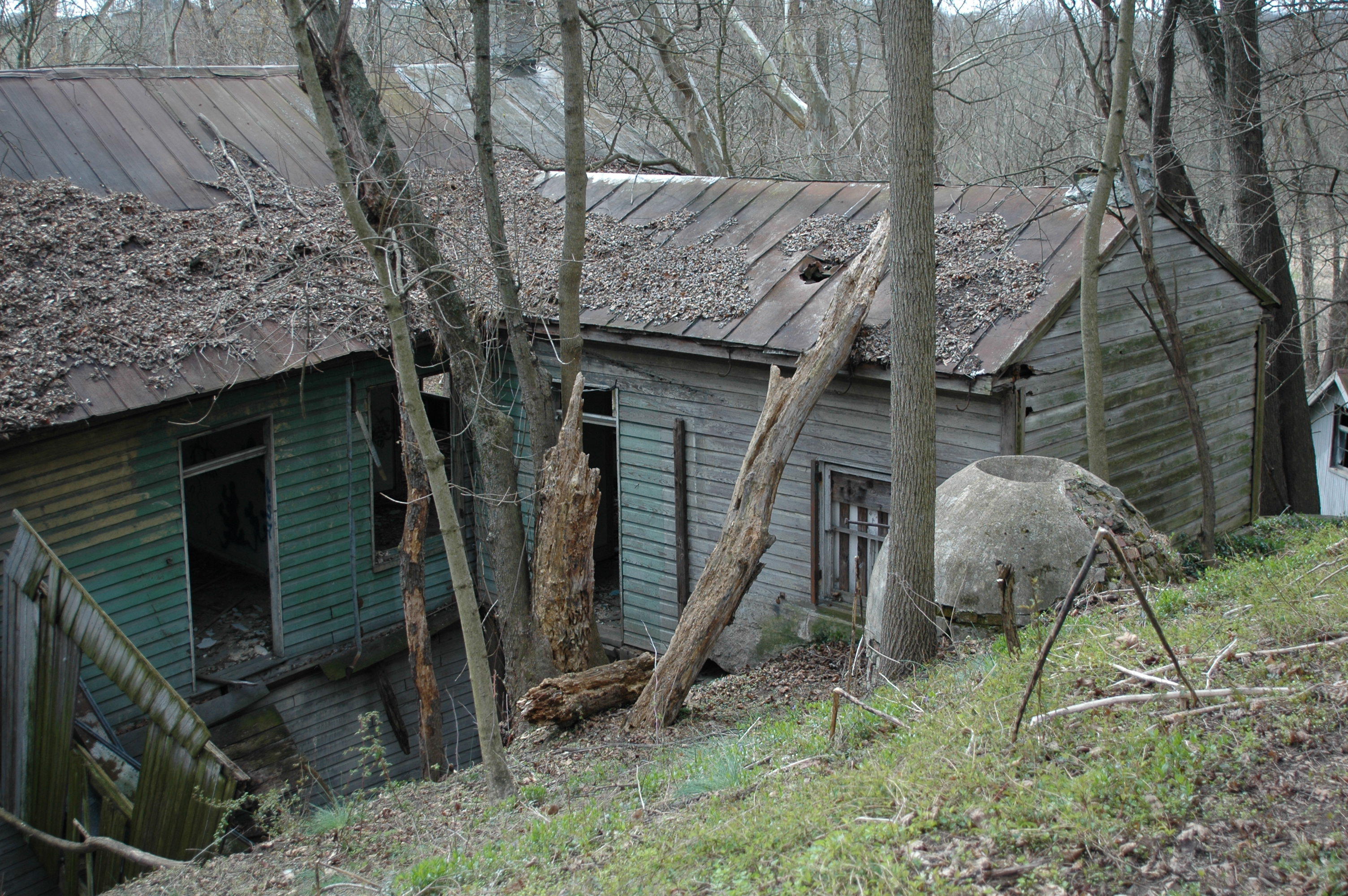 an abandoned and broken-down house on a slope in the woods